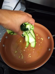 zucchini pasta tossing in oil in pan 