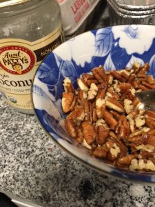 chopped pecans with coconut oil in bowl